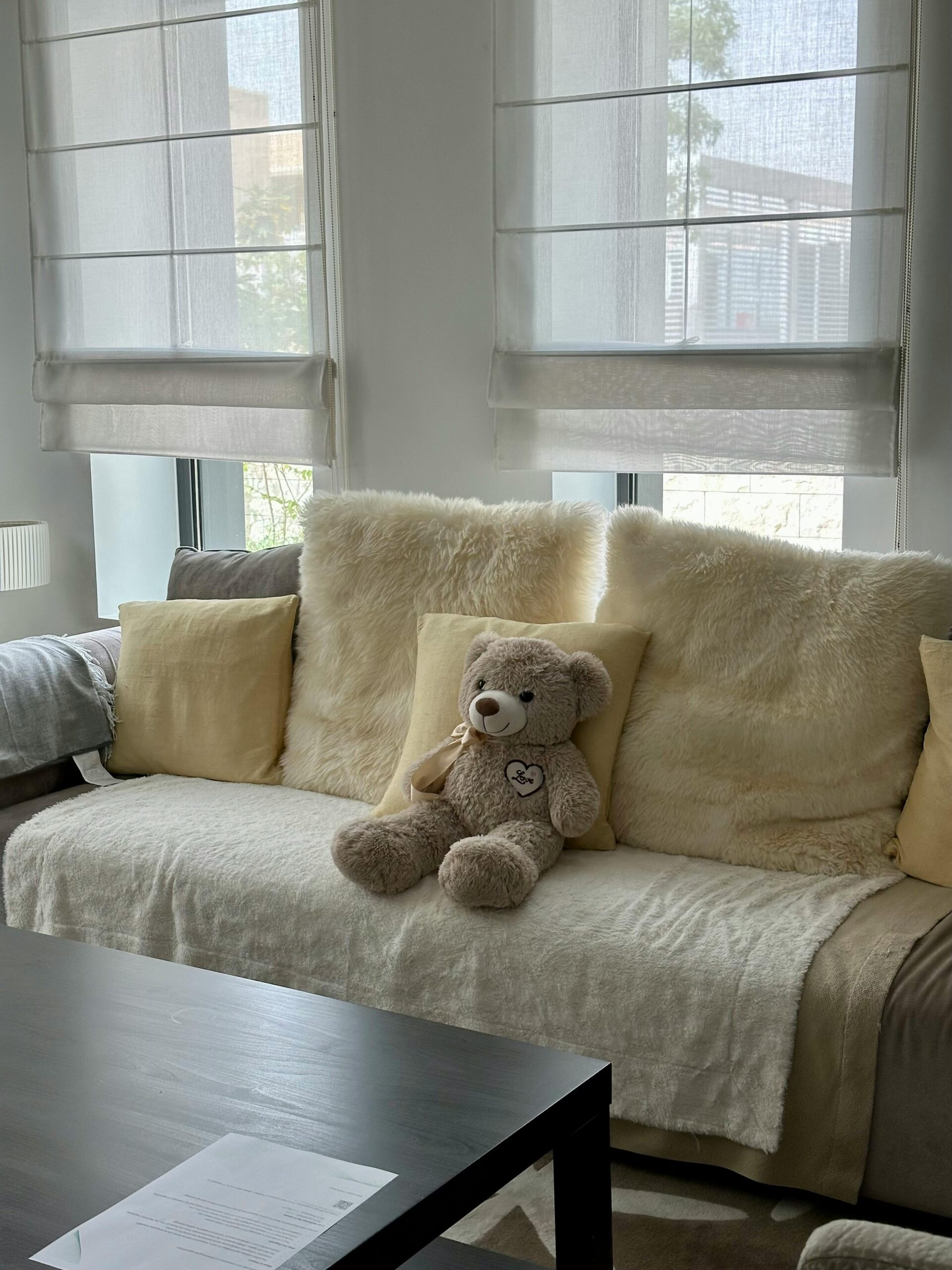 Inviting living room features a sofa adorned with cushions and a fuzzy teddy bear, perfect for relaxation.