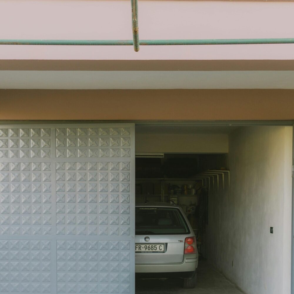 Partially open garage with parked car visible inside, featuring a modern sliding door design.